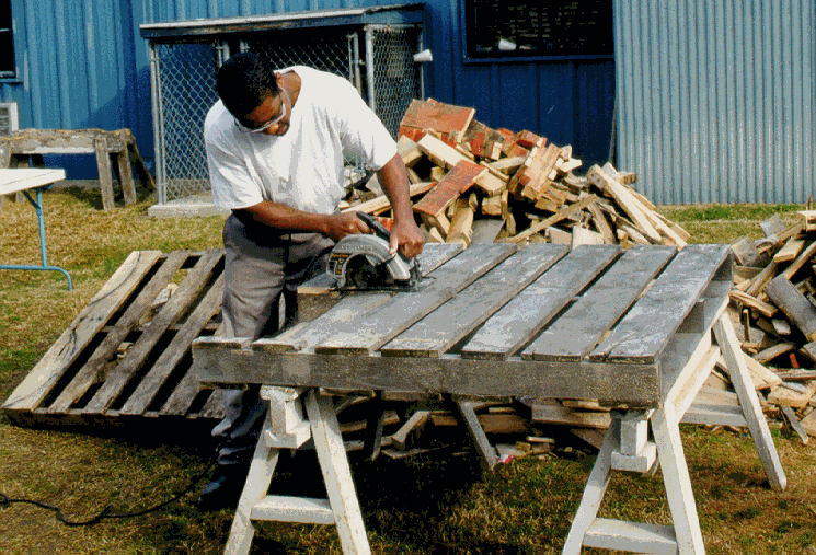 An inmate saws usable boards from a palette. The boards are used to create bluebird nest box kits.